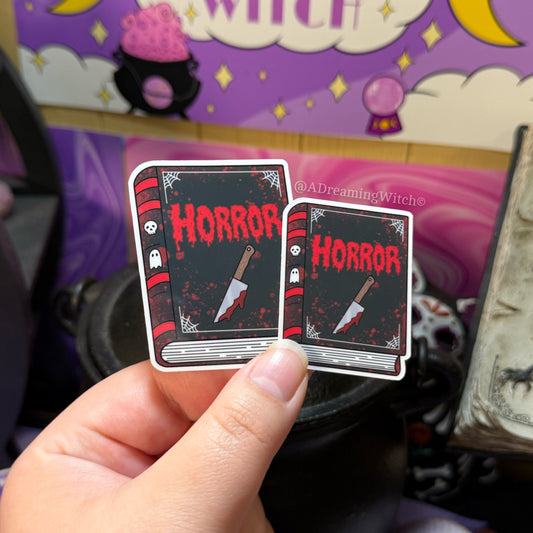 Two 'Horror' themed book stickers held by a hand with a witchy-themed background.