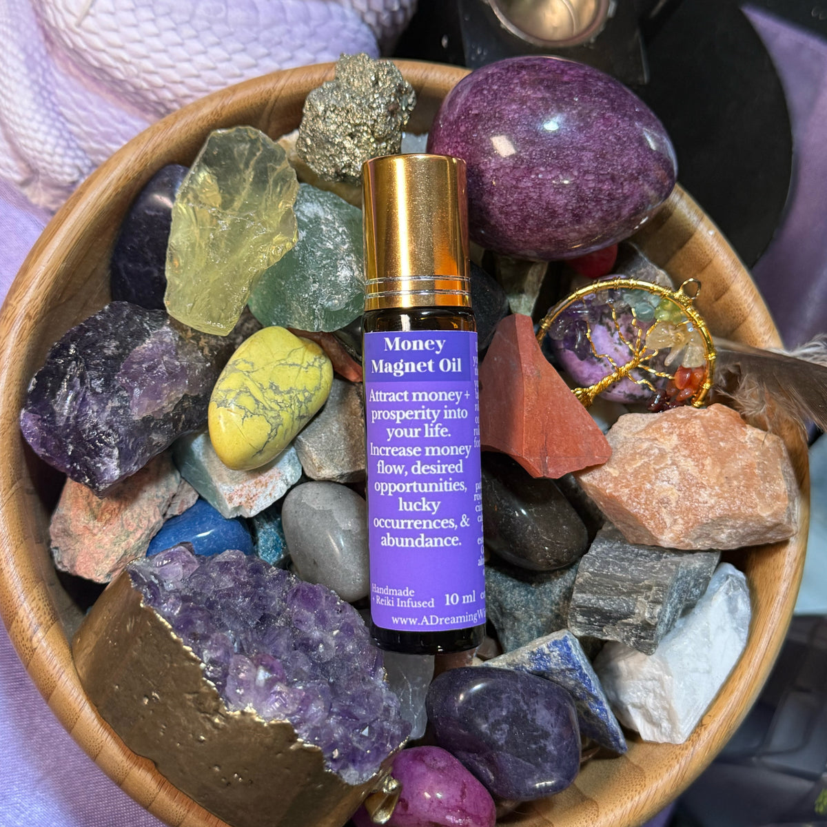 Money magnet oil bottle on a bed of colorful crystals and stones.