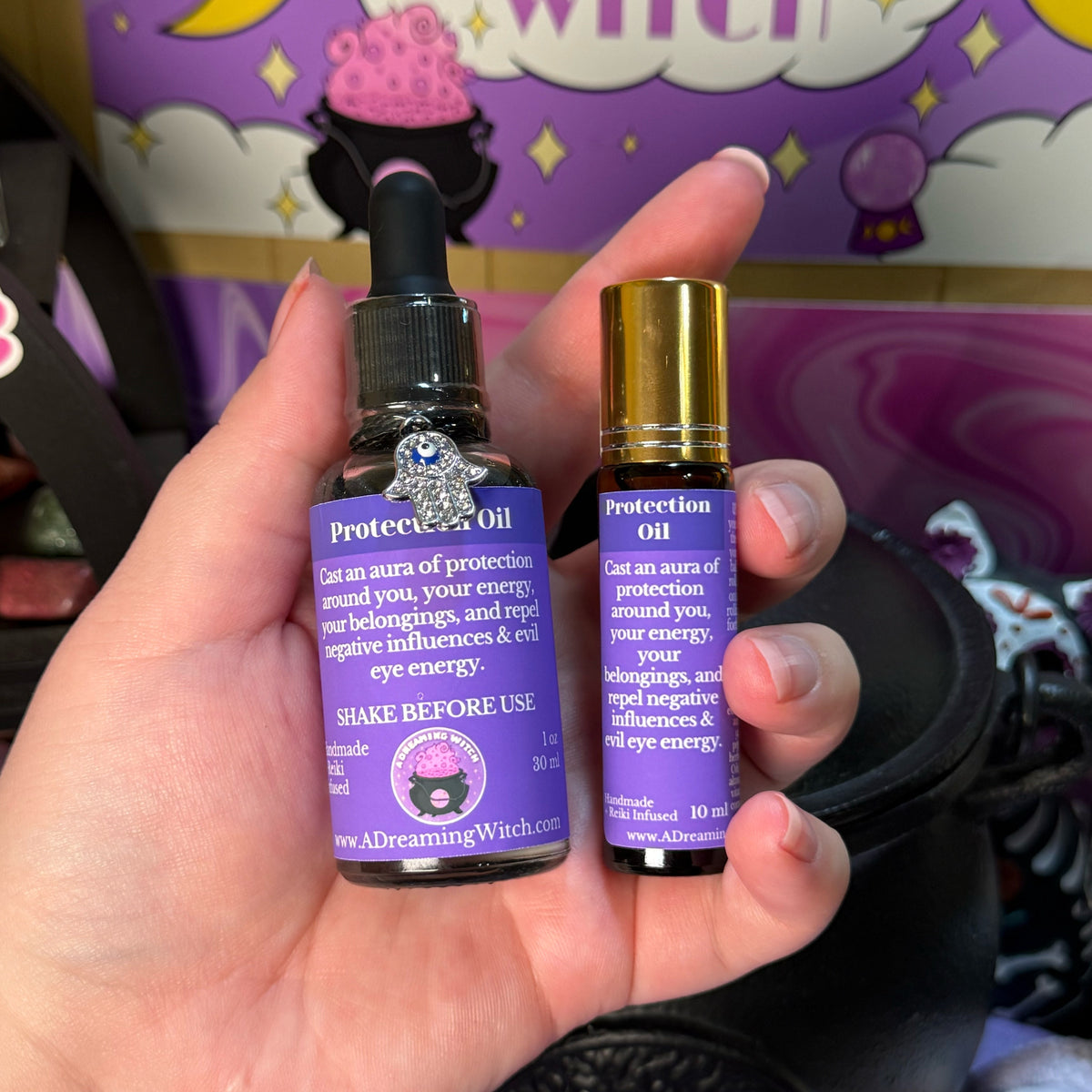 Two bottles of 'Protection Oil' held in a hand with a colorful background