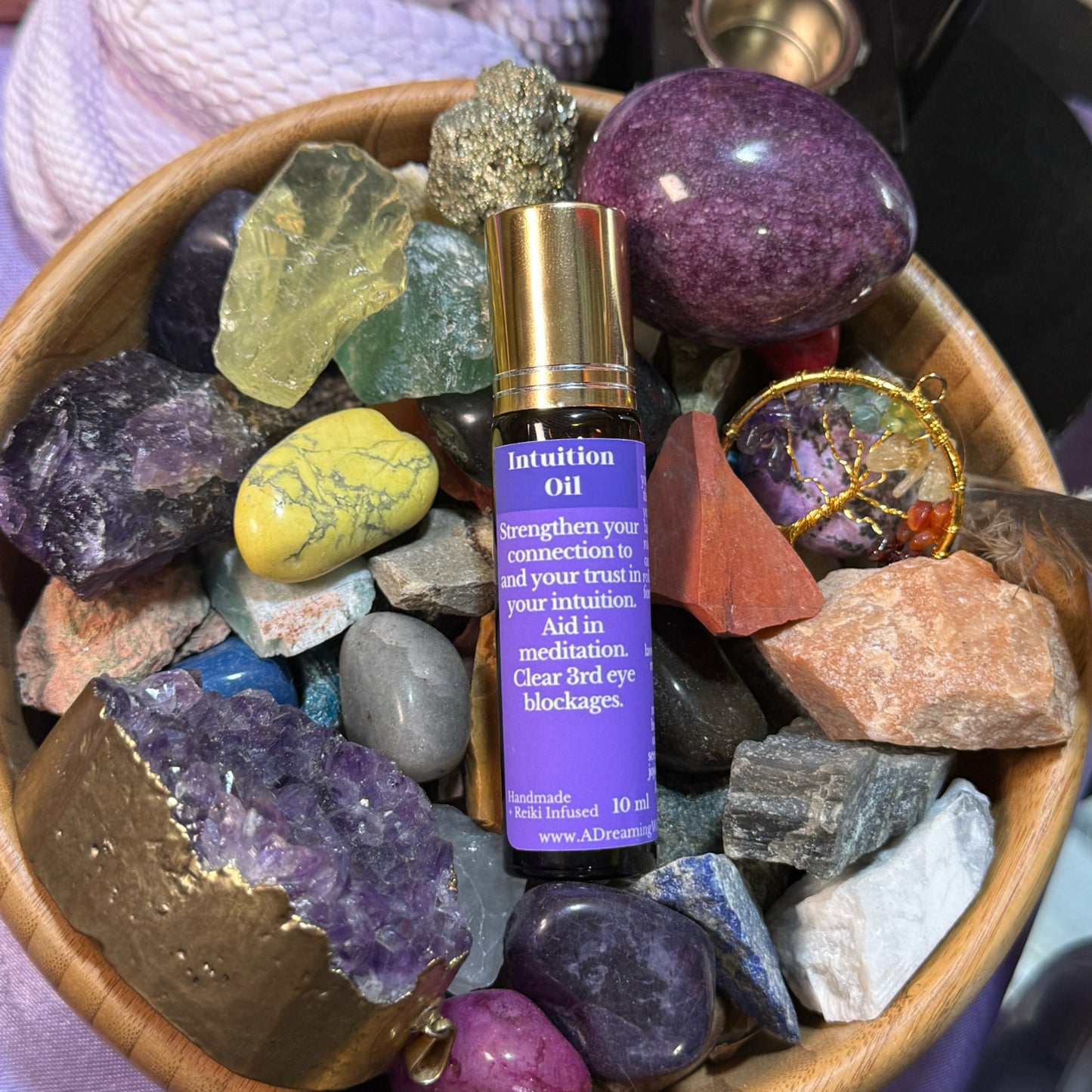 Intuition oil bottle surrounded by colorful crystals in a wooden bowl