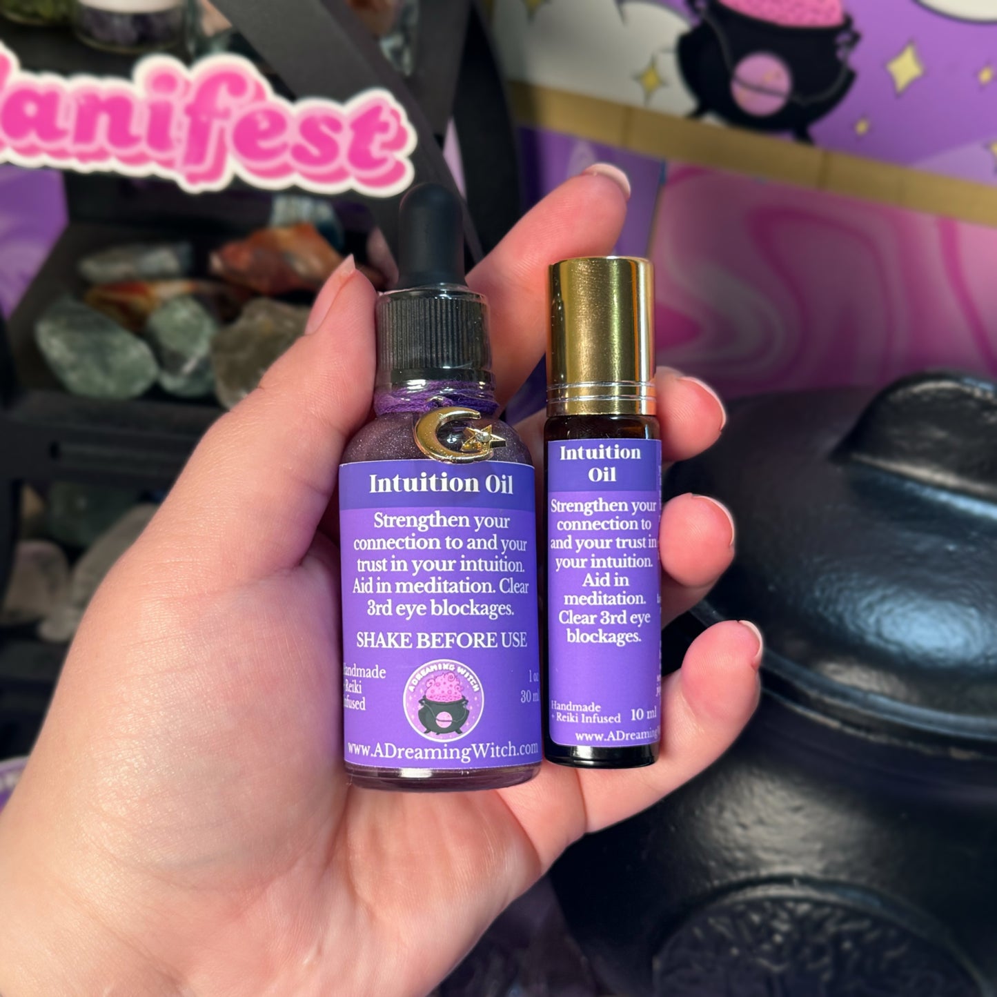 Two Intuition Oil bottles held in a hand with a colorful background.