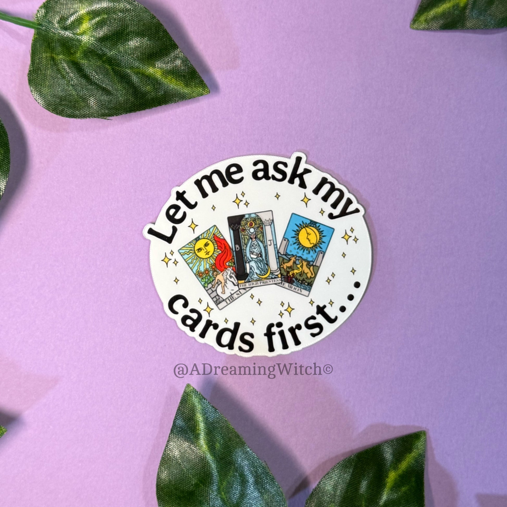 Sticker with tarot card designs and text on a purple background with leaves.