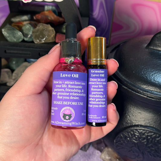 Hand holding two bottles of 'Love Oil' with purple labels against a blurred background.