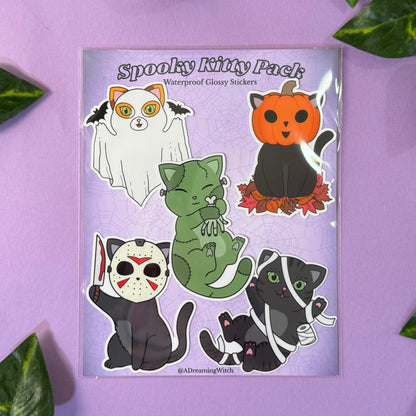Spooky Kitty Pack stickers on a purple background with green leaves.