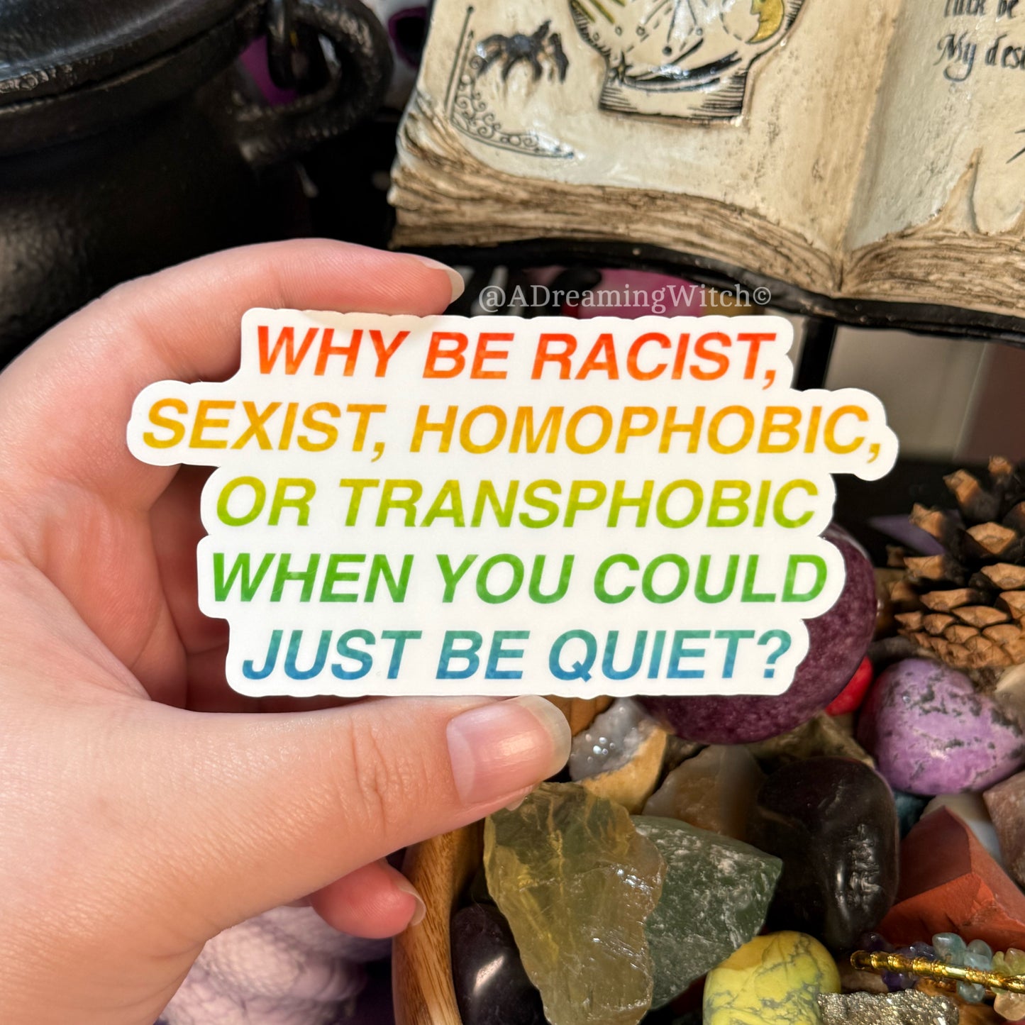 Hand holding a sign with anti-racism message amidst stones and books