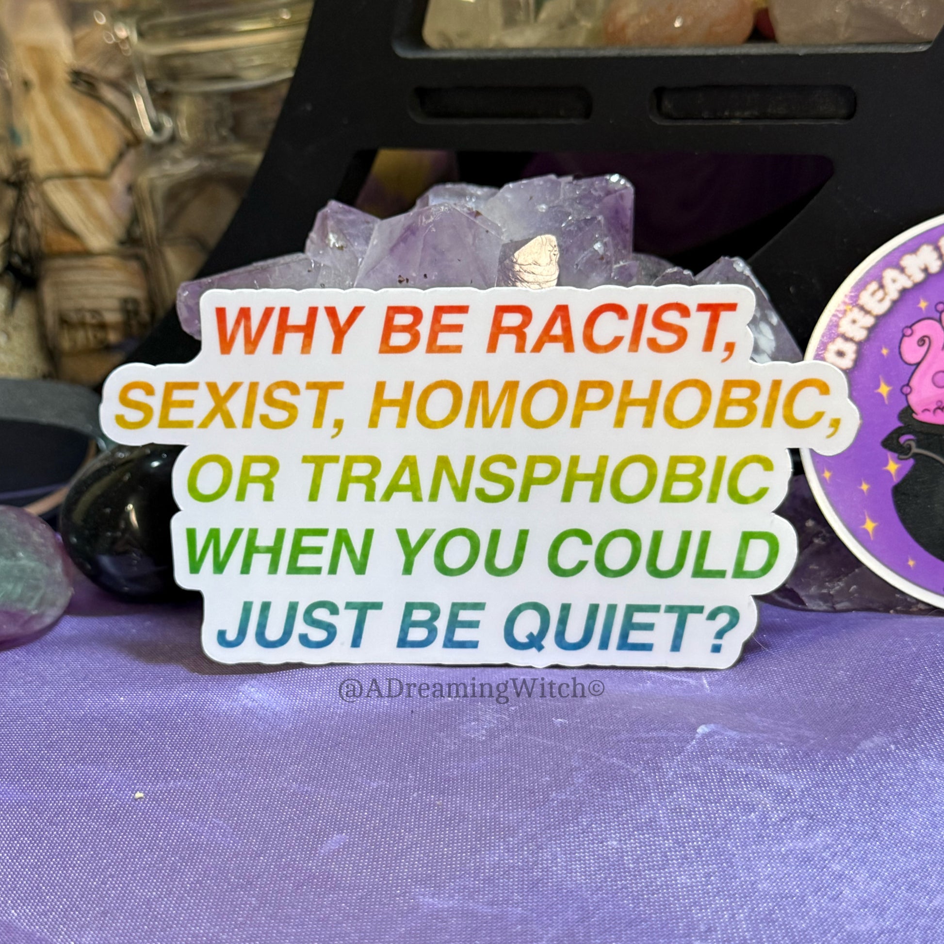 Sticker with anti-racism and anti-harassment message on a purple fabric background