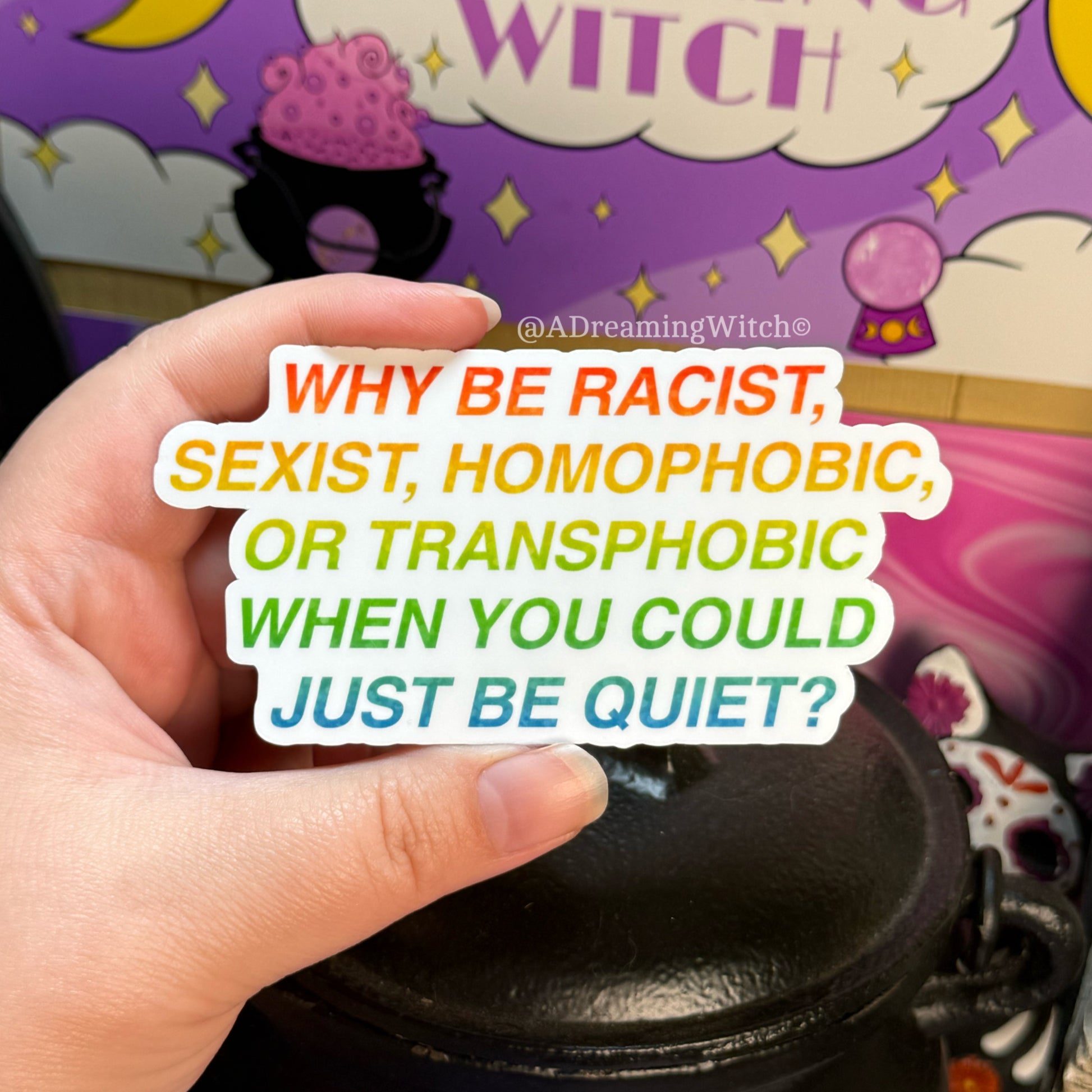 Hand holding a sticker with anti-racism message in front of a colorful background with text and graphics.